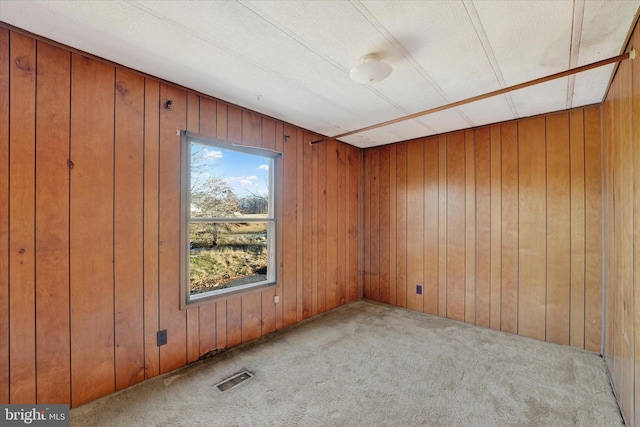 carpeted spare room with wood walls