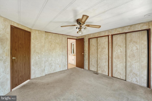 unfurnished bedroom with ceiling fan, carpet flooring, and multiple closets