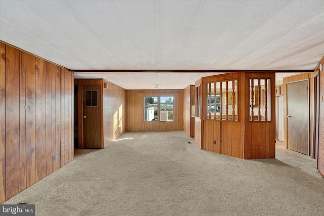 carpeted spare room with wood walls and a textured ceiling