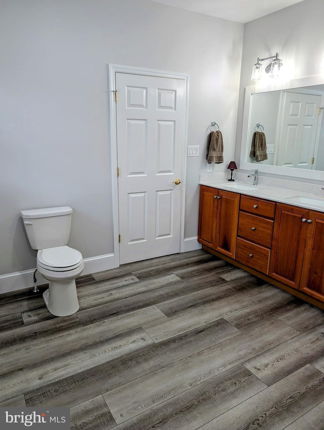 bathroom featuring toilet, vanity, and wood-type flooring