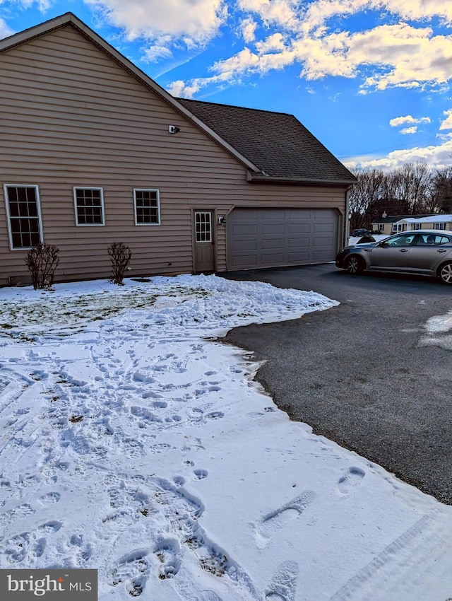 snow covered property with a garage