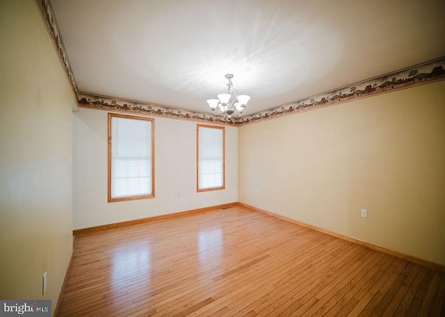 unfurnished room featuring wood-type flooring and an inviting chandelier