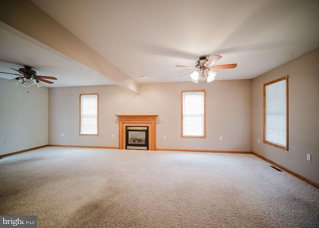 unfurnished living room with ceiling fan, plenty of natural light, and carpet floors