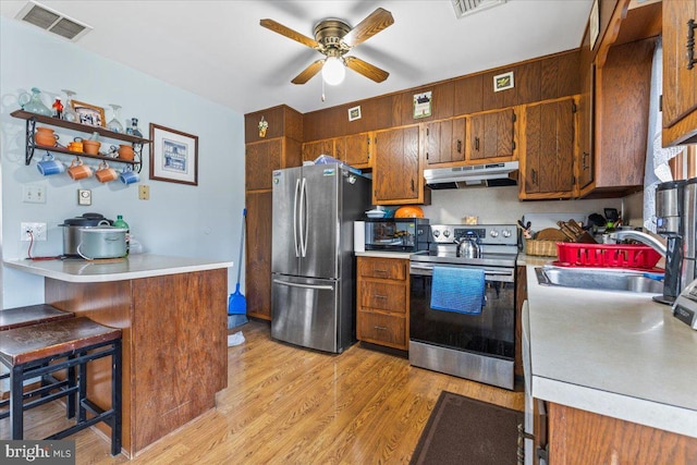 kitchen featuring appliances with stainless steel finishes, light hardwood / wood-style floors, kitchen peninsula, a breakfast bar, and sink