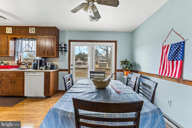 dining area featuring sink, baseboard heating, light wood-type flooring, and ceiling fan