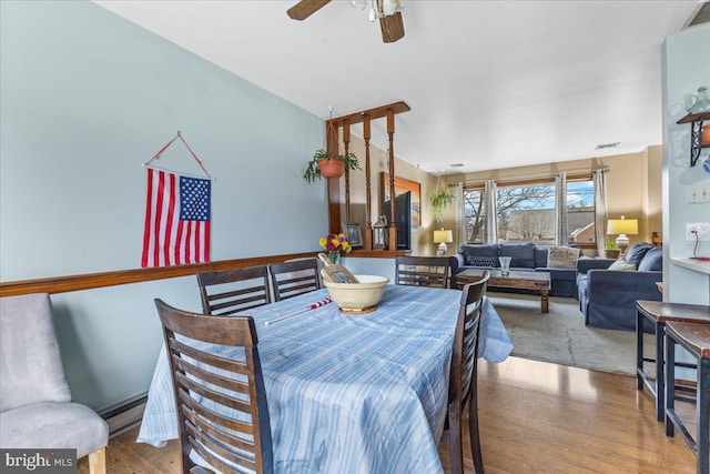 dining area with wood-type flooring, a baseboard heating unit, and ceiling fan