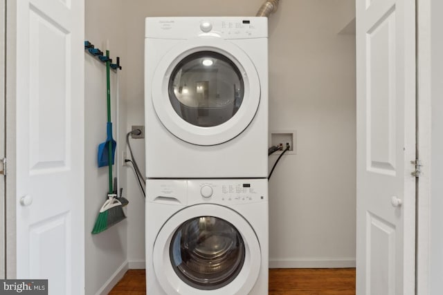 laundry area with hardwood / wood-style flooring and stacked washing maching and dryer