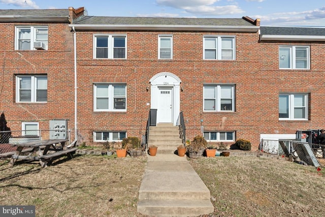 townhome / multi-family property with cooling unit and a front lawn