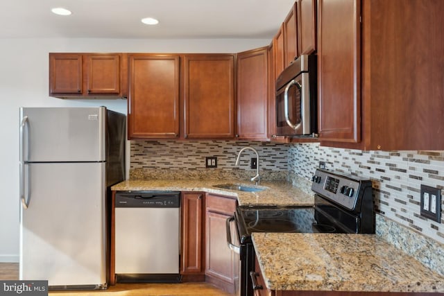 kitchen featuring appliances with stainless steel finishes, light stone countertops, sink, and backsplash