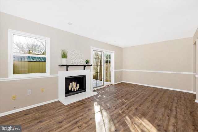 unfurnished living room with dark wood-type flooring and a wealth of natural light