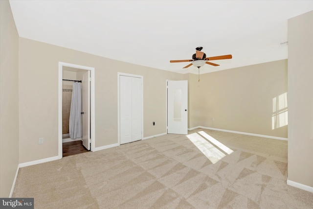 unfurnished bedroom featuring ceiling fan, light colored carpet, and connected bathroom