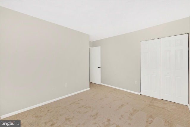 unfurnished bedroom featuring a closet and light carpet