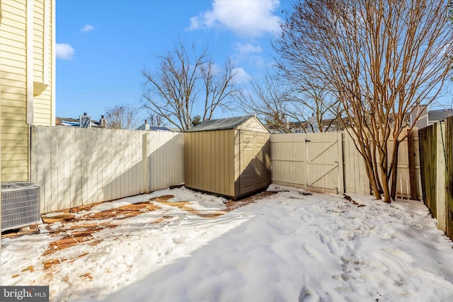 snowy yard with central air condition unit and a storage shed