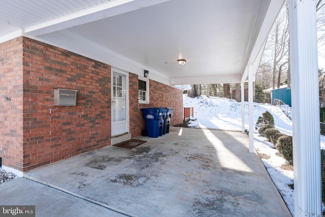 snow covered patio with a carport