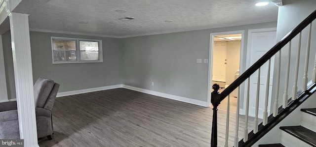 basement featuring a textured ceiling, dark hardwood / wood-style flooring, and ornamental molding