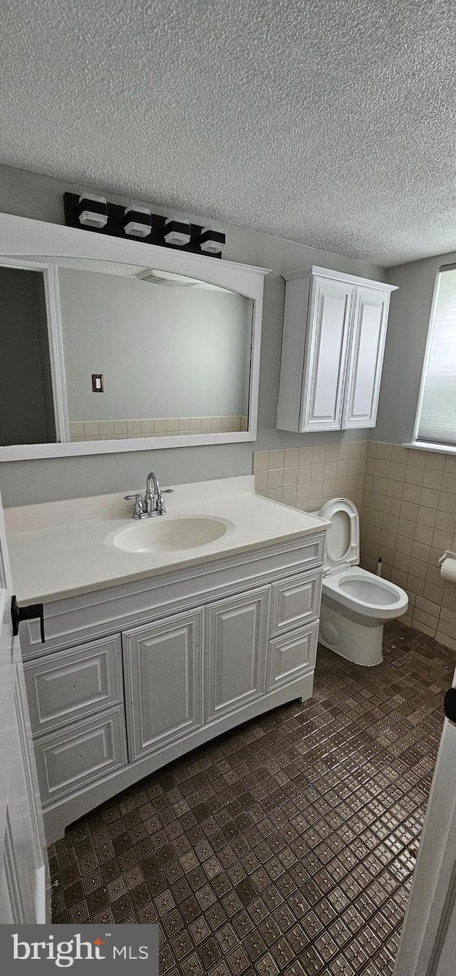 bathroom with vanity, tile walls, and toilet