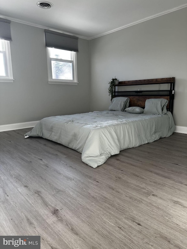 bedroom featuring multiple windows, ornamental molding, and hardwood / wood-style flooring