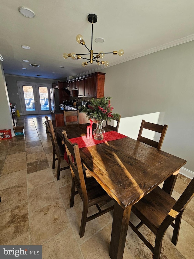 dining room with a notable chandelier, crown molding, and french doors