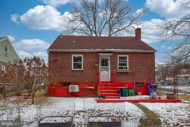 snow covered back of property featuring a wall mounted air conditioner