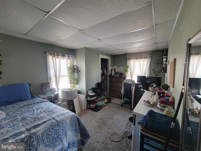 carpeted bedroom featuring cooling unit, a closet, and a drop ceiling