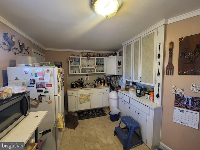 kitchen with white refrigerator, white cabinets, sink, and crown molding