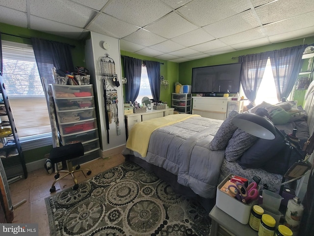 bedroom featuring a drop ceiling and multiple windows