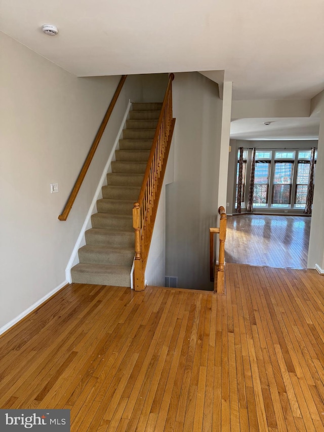 stairway featuring visible vents, baseboards, and wood-type flooring