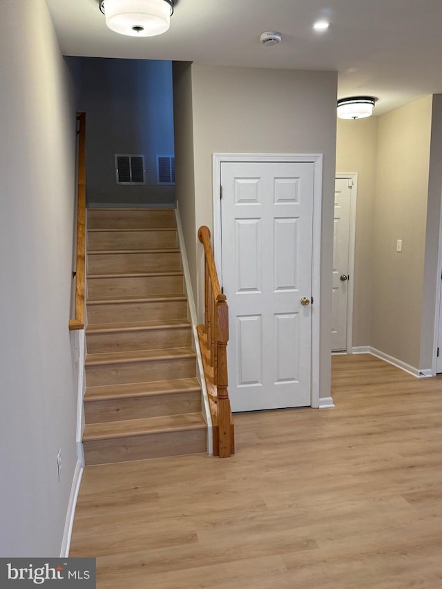 stairs with wood finished floors, visible vents, and baseboards