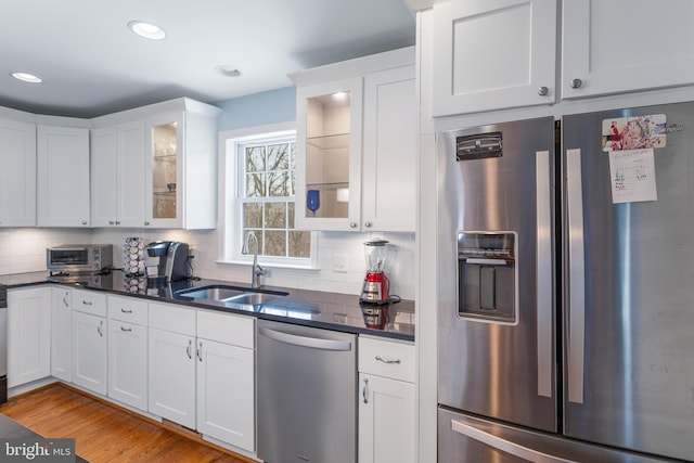 kitchen with sink, white cabinets, stainless steel appliances, and light wood-type flooring