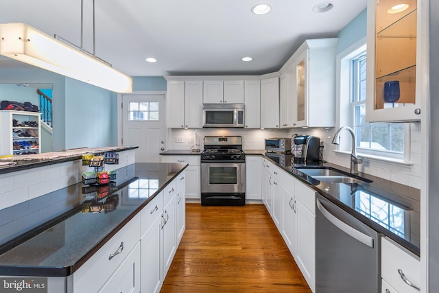 kitchen featuring white cabinets, appliances with stainless steel finishes, decorative light fixtures, decorative backsplash, and sink