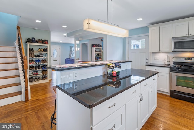 kitchen with pendant lighting, appliances with stainless steel finishes, a center island, white cabinetry, and a breakfast bar