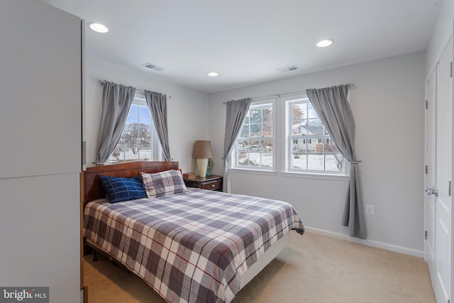 bedroom featuring light colored carpet and multiple windows