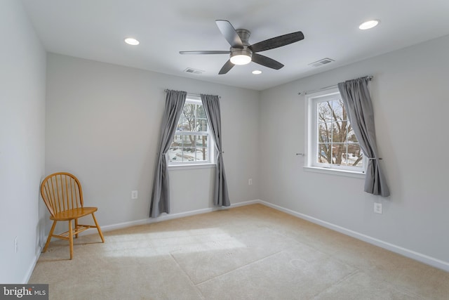 spare room with ceiling fan, light colored carpet, and plenty of natural light