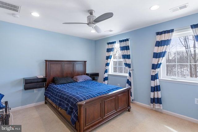 bedroom featuring ceiling fan, light colored carpet, and multiple windows