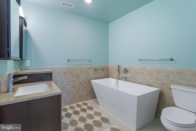 bathroom with tile patterned flooring, tile walls, toilet, vanity, and a washtub