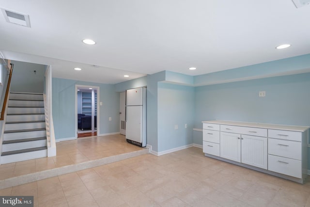 kitchen with white refrigerator, white cabinetry, and light tile patterned flooring