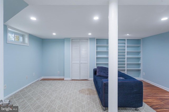 basement with built in shelves and light hardwood / wood-style flooring