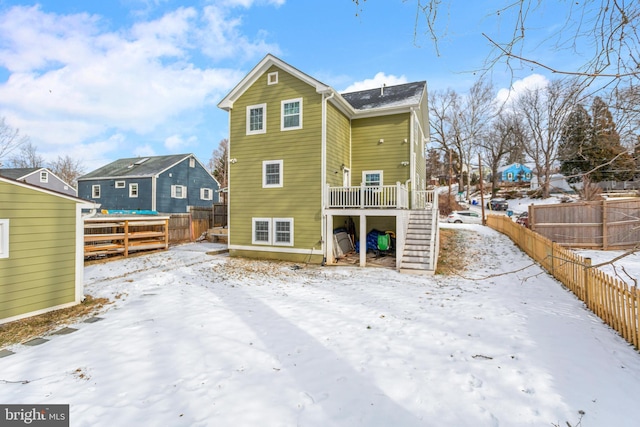 snow covered back of property with a deck