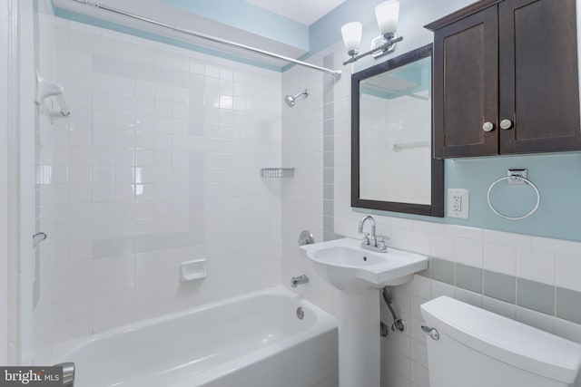 bathroom featuring tile walls, toilet, and tiled shower / bath