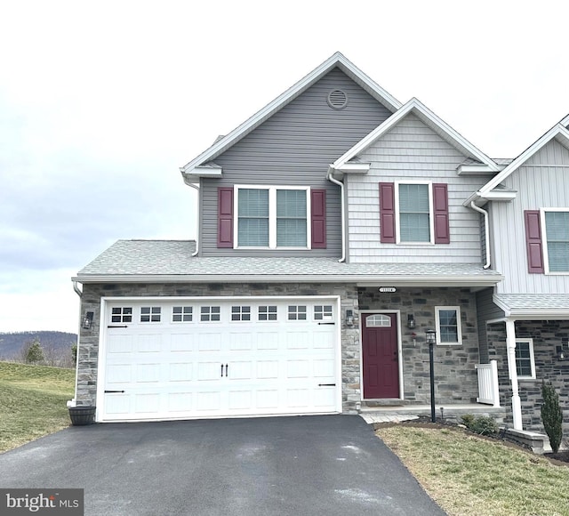 multi unit property featuring aphalt driveway, stone siding, a shingled roof, and a garage