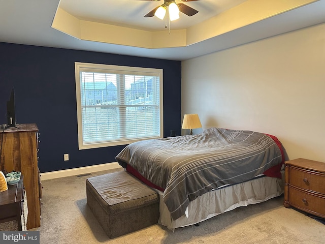 carpeted bedroom with a raised ceiling, visible vents, ceiling fan, and baseboards