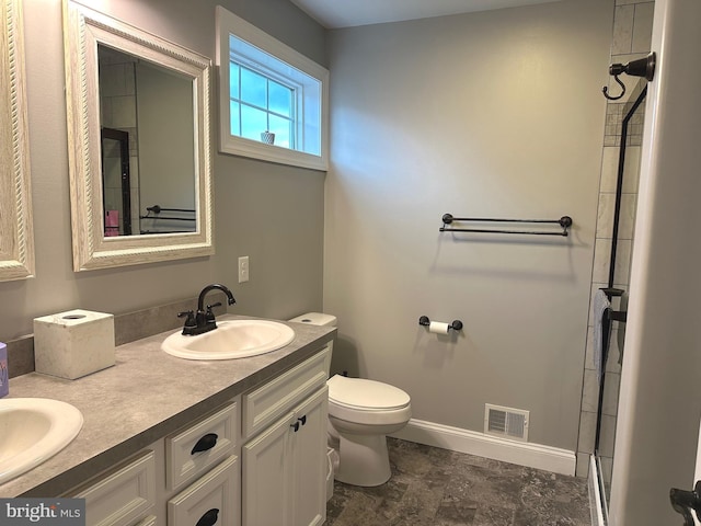 bathroom with double vanity, baseboards, visible vents, toilet, and a sink