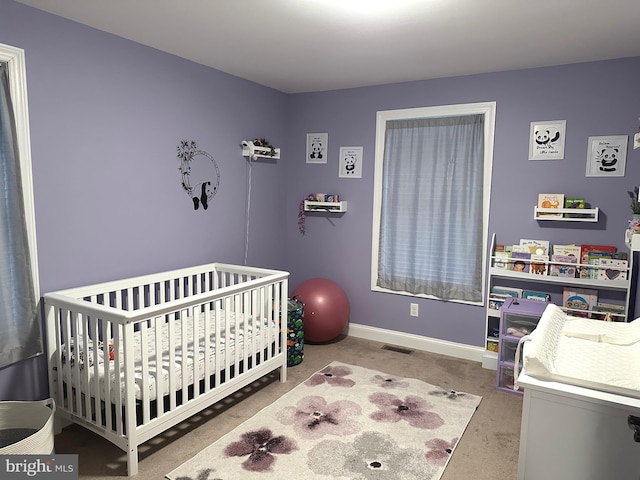 bedroom featuring carpet floors, a crib, visible vents, and baseboards