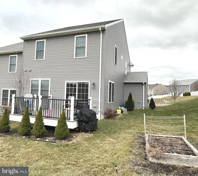 back of house featuring a deck, a yard, and a garden