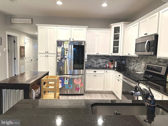 kitchen with stainless steel appliances, backsplash, and white cabinetry