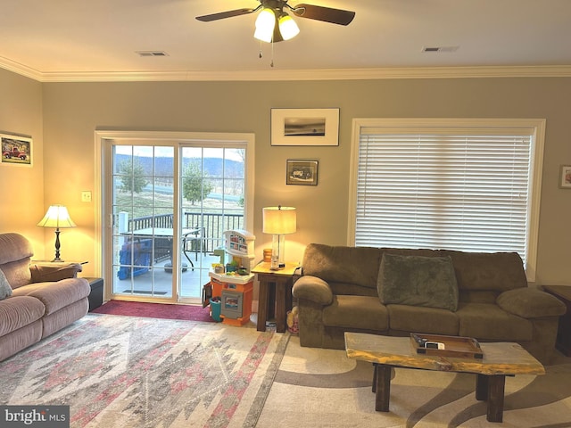 living area with ornamental molding, carpet, visible vents, and a ceiling fan