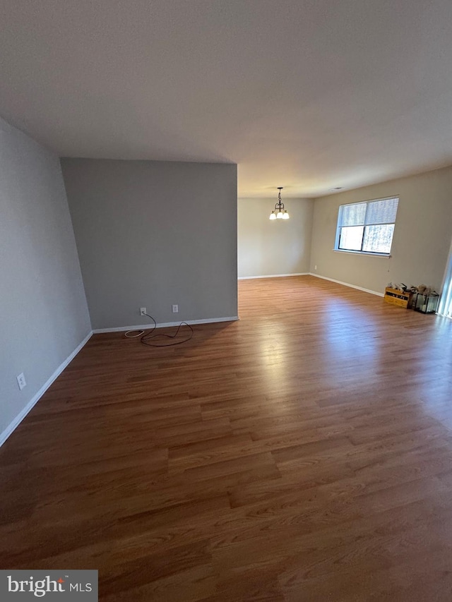 unfurnished room featuring dark hardwood / wood-style flooring and an inviting chandelier