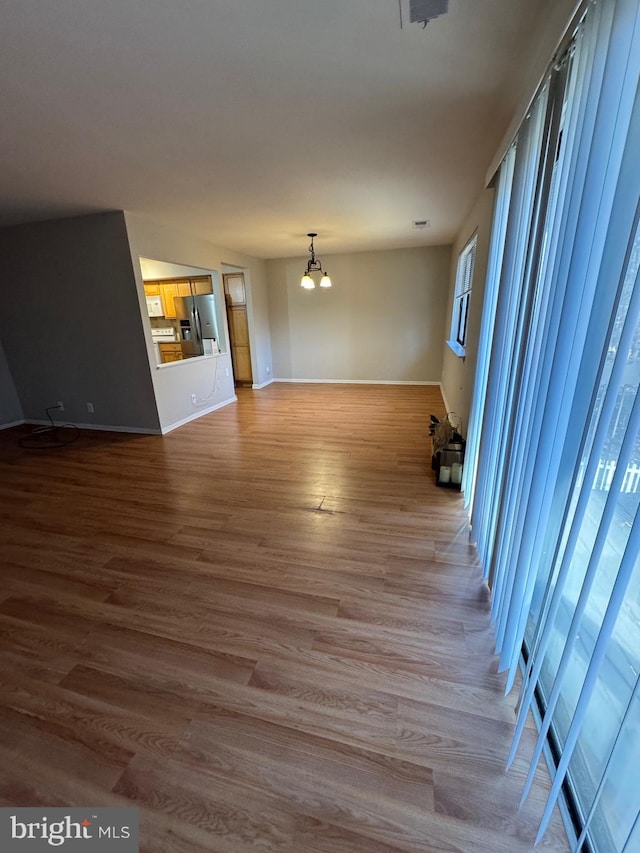 unfurnished living room featuring wood-type flooring and an inviting chandelier