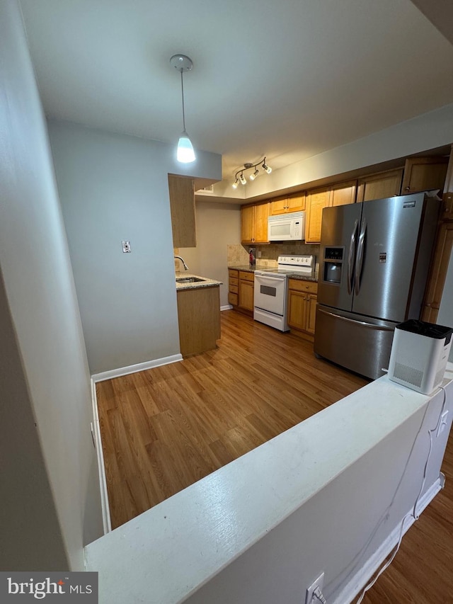 kitchen featuring sink, tasteful backsplash, hardwood / wood-style floors, pendant lighting, and white appliances