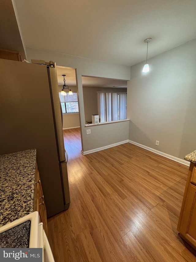 interior space featuring a chandelier, light wood-type flooring, and stainless steel refrigerator